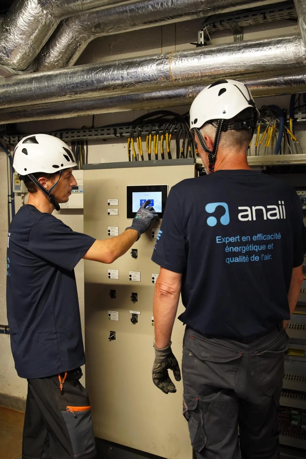 Techniciens ANAII devant une armoire de commande dans un local technique